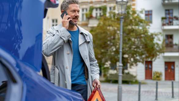 Man standing behind BMW trunk BMW 5 Series Sedan G30 Man standing at BMW trunk with Smartphone and warning triangle BMW 5 Series Sedan G30