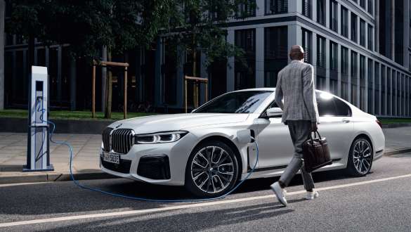 BMW 745e Sedan plug-in hybrid G11 G12 Mineral White three-quarter side view charging BMW 745e Sedan plug-in hybrid G11 G12 Mineral White three-quarter side view charging with model