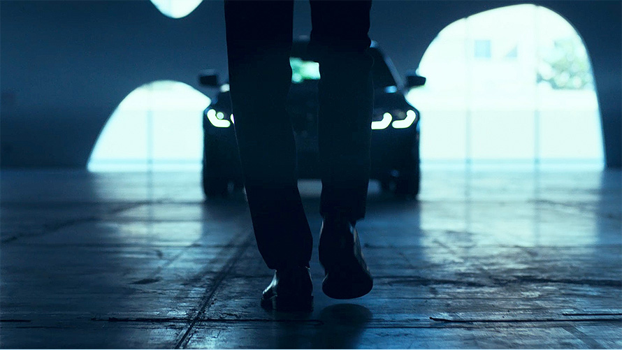BMW ซีรีส์ 3 Sedan (G20), มุมมองด้านหน้า มุมมองจากด้านหลังของผู้ชายที่กำลังเดินเข้าหาด้านหน้าของ BMW ซีรีส์ 3 Sedan (G20) บนถนนราดยางมะตอย