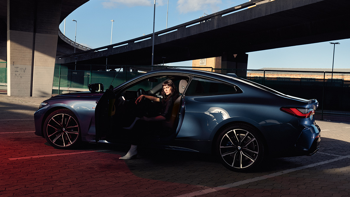 ภาพด้านข้าง BMW ซีรีส์ 4 Coupé G22 2020 ล้ออัลลอยน้ำหนักเบา ภาพด้านข้าง BMW ซีรีส์ 4 Coupé G22 2020 สี Artic Race Blue metallic ล้ออัลลอยน้ำหนักเบาเปิดประตูโดยมีนางแบบนั่งอยู่ในรถ