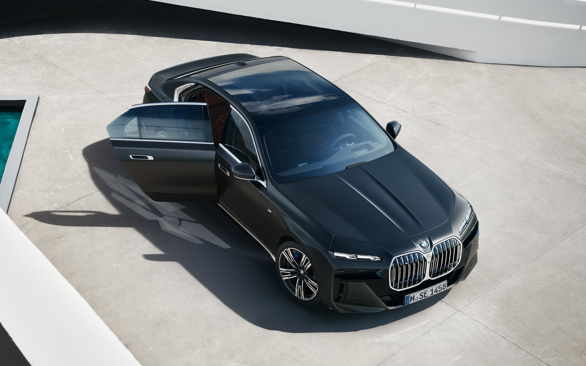 ภาพมุมสูงของ BMW 7 Series Sedan G70 ICE 740i แพ็คเกจ M Sport สี Frozen Deep Grey metallic ภาพมุมสูงของ BMW 7 Series Sedan G70 ICE 740i แพ็คเกจ M Sport สี Frozen Deep Grey metallic ขณะเปิดประตูผู้โดยสารไว้