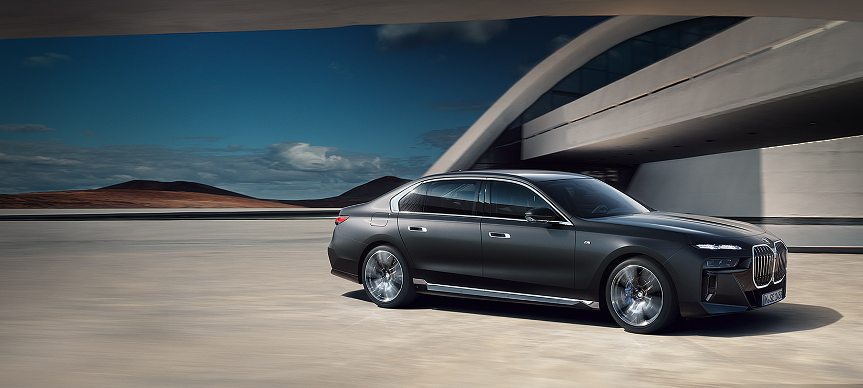มุมมองด้านหน้า 3/4 ส่วนของ BMW 7 Series Sedan G70 ICE แพ็คเกจ M Sport สี Frozen Deep gray metallic จอดอยู่หน้าอาคาร
