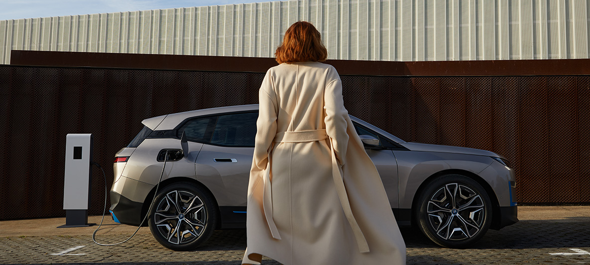 BMW iX Cashmere Silver i20 side view standing with model in front