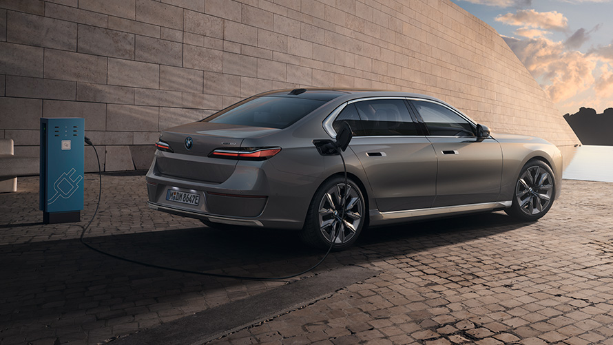 มุมมองด้านหลัง 3/4 ส่วนของ BMW i7 Sedan G70 มุมมองด้านหลัง 3/4 ส่วนของ BMW i7 Sedan G70 สี Oxid grey metallic จาก BMW Individual ที่สถานีชาร์จ