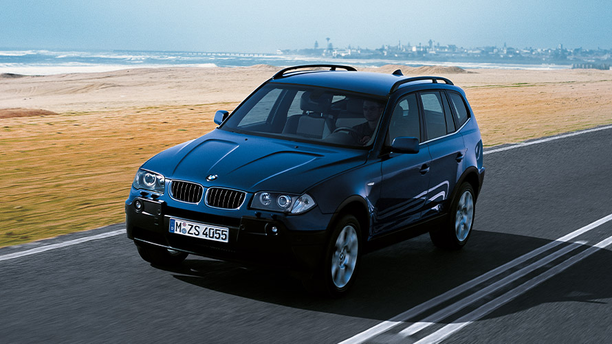 BMW X3 E83 first generation three-quarter front view driving on the street BMW X Series BMW X3 E83 first generation three-quarter front view driving on the street
