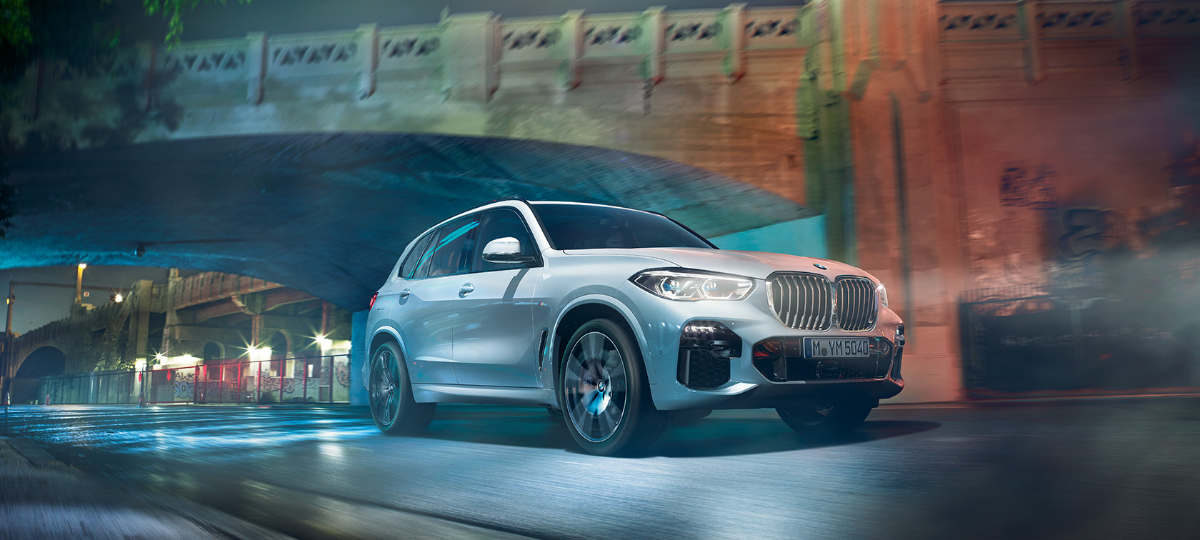 มุมมองด้านหน้าแบบสามในสี่ส่วนของ BMW X5 G05 2018 สี Mineral White metallic ขณะขับขี่ยามค่ำคืน