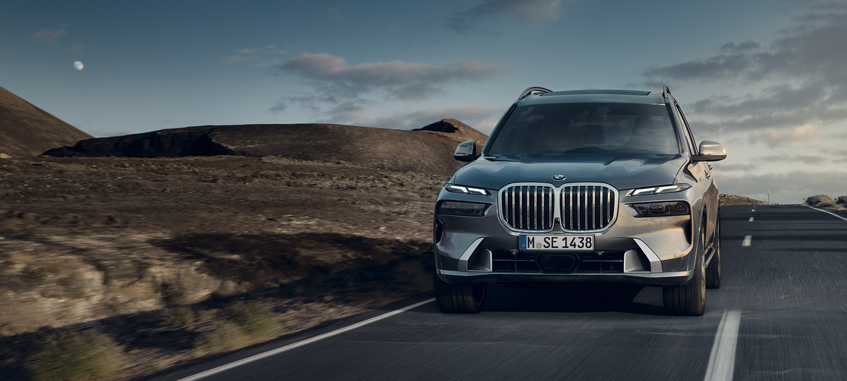 มุมมองด้านหน้าแบบ 7/8 ของ BMW X7 G07 LCI สี Sparkling Copper Grey metallic ขณะขับขี่