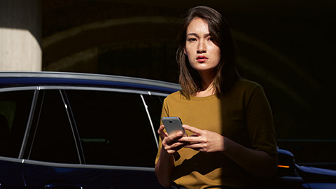 BMW ConnectedDrive Overview BMW ConnectedDrive Overview woman with smartphone in her hands with BMW in the background