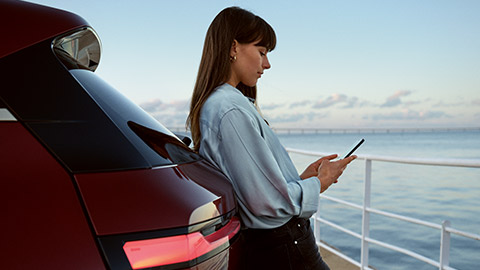 My BMW App BMW ConnectedDrive BMW ConnectedDrive My BMW App woman leaning against BMW with smartphone in her hands