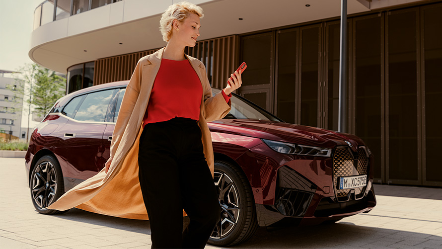 My BMW App Woman with smartphone in front of a BMW Woman with smartphone in front of a BMW