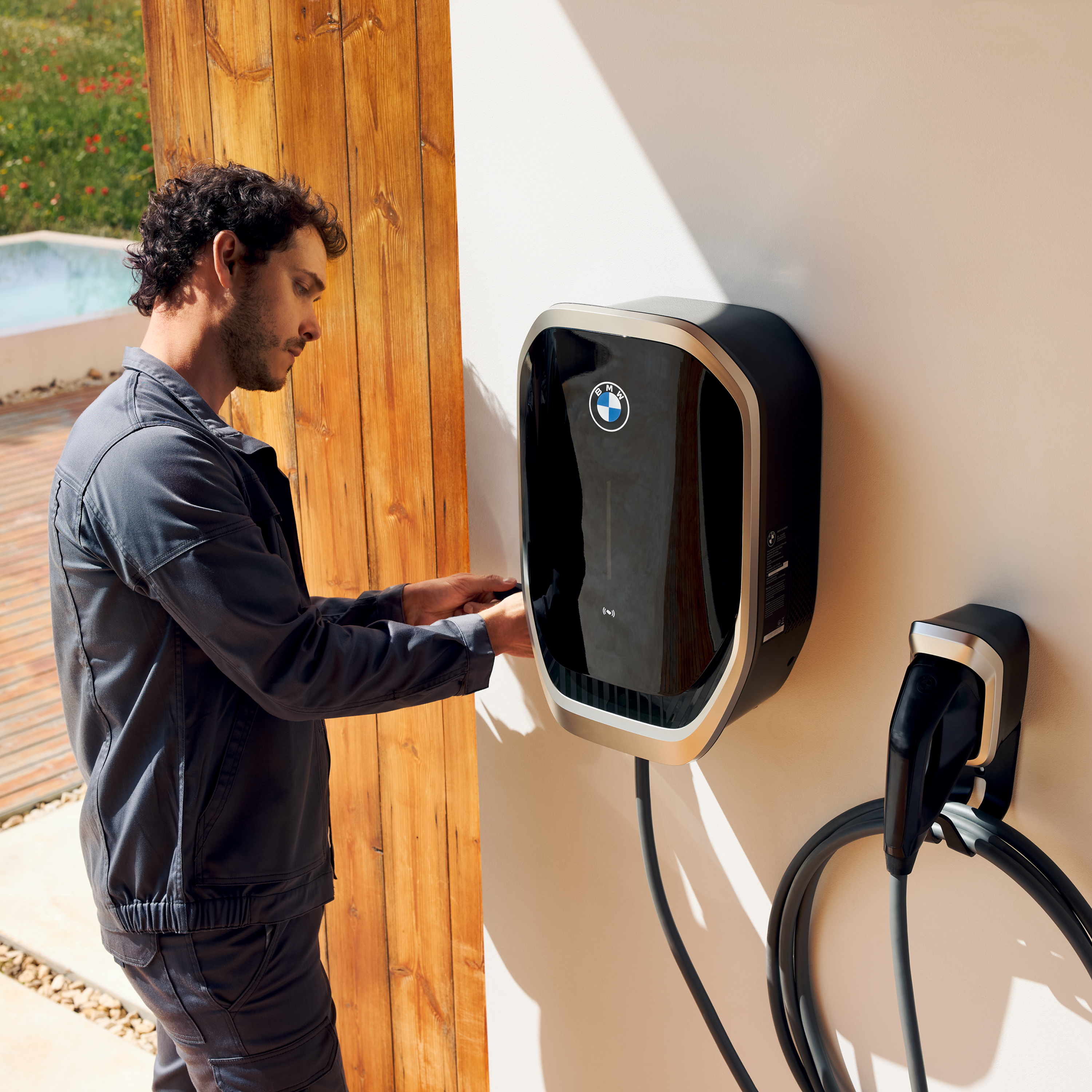 คนกำลังเสียบสายชาร์จเข้ากับ BMW Wallbox