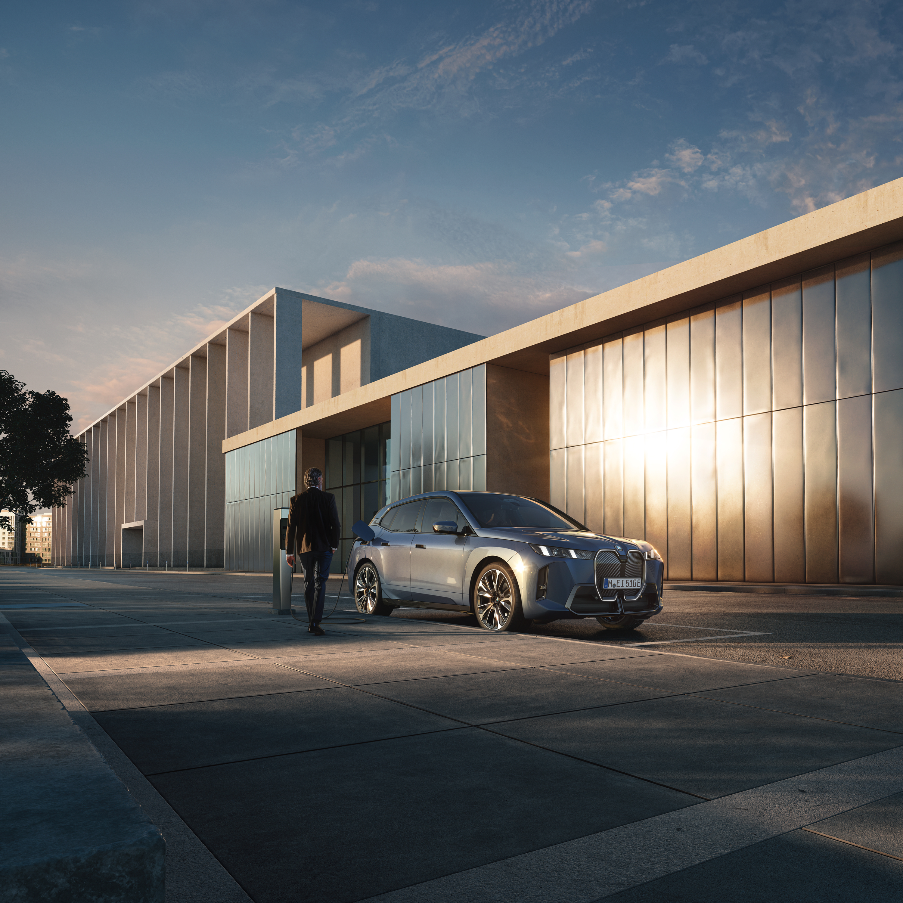คนกำลังเดินไปยังรถยนต์ BMW ที่กำลังชาร์จอยู่