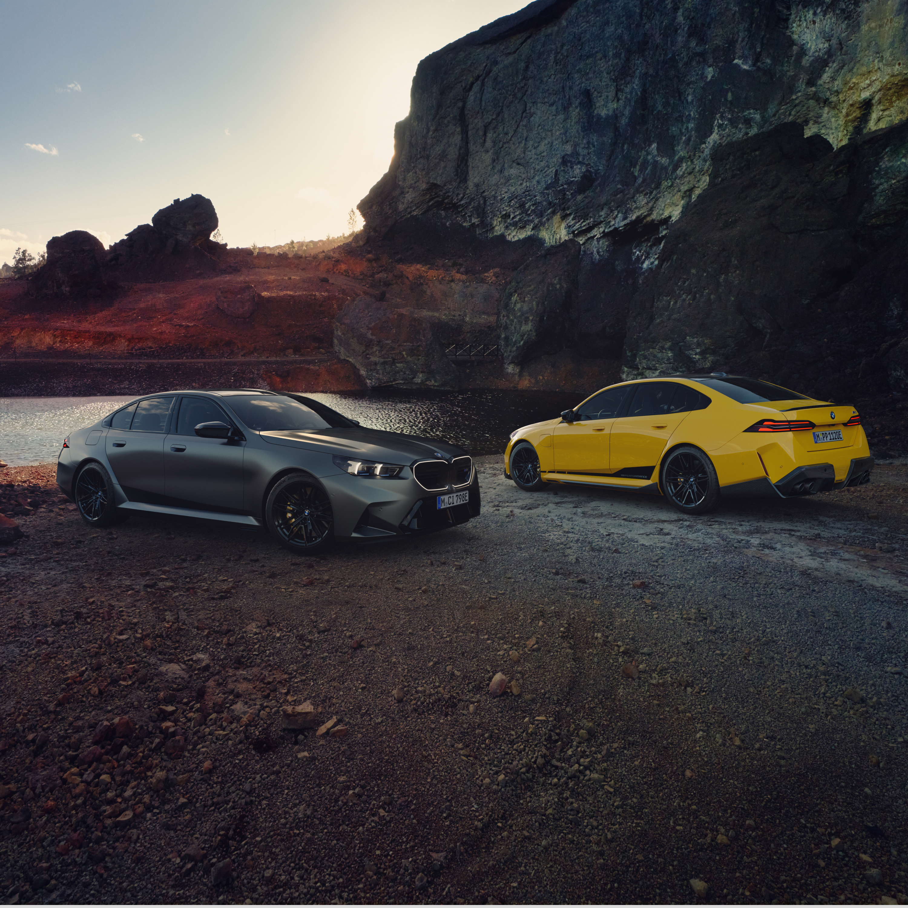 รถยนต์ BMW ซีรีส์ 5 สองคันจอดบนชายหาดด้านหน้าผนังหิน